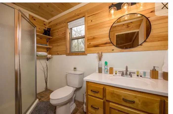 Warm cabin bath with glass shower, stocked vanity, and natural light