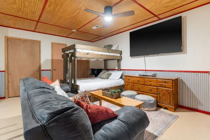 Cozy bunk room lounge with big TV, comfy sofa, and rustic wood accents