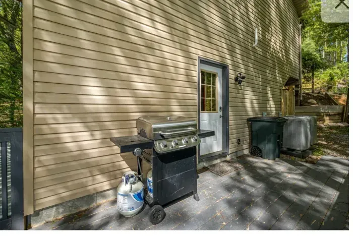 Shaded side patio with gas grill—easy outdoor cooking by the woods