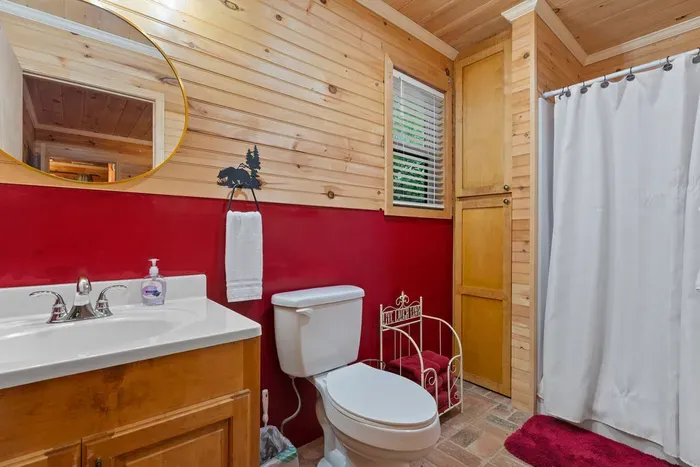 Cozy cabin-style bathroom with wood accents, storage, and a full shower