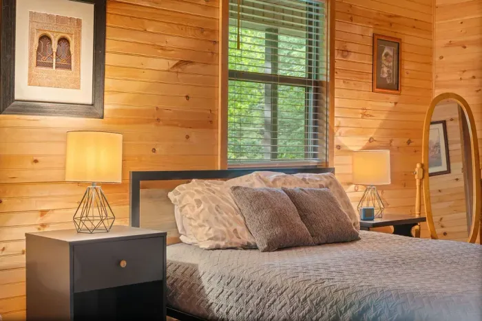 Cozy wood-paneled bedroom with soft lighting and peaceful forest views