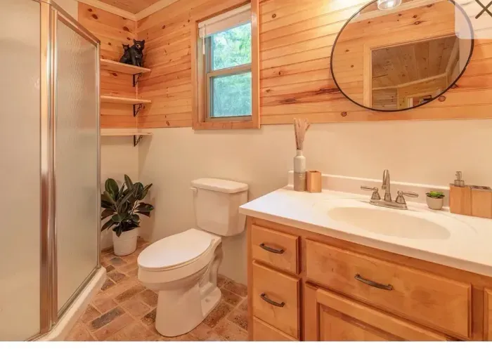 Cozy cabin-style bath with walk-in shower, natural wood and bright vanity.