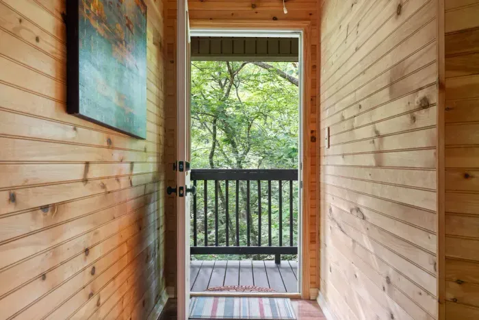 Cozy wood-lined entry opening to a private deck in the trees