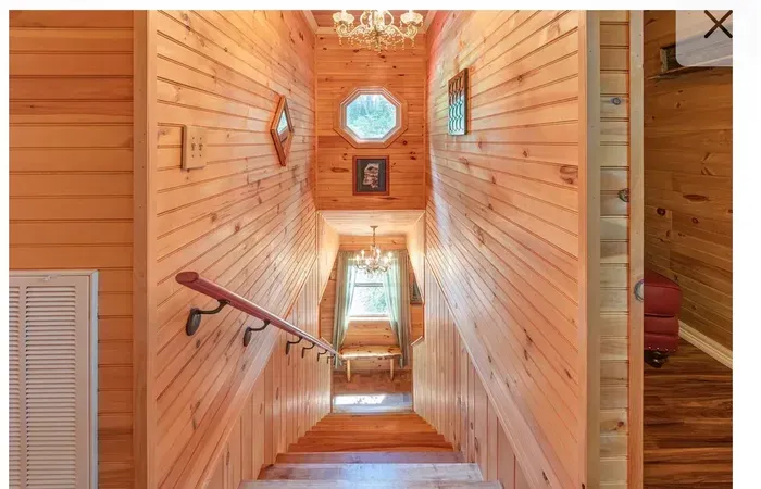 Sunlit pine stairwell with chandeliers and cozy cabin character