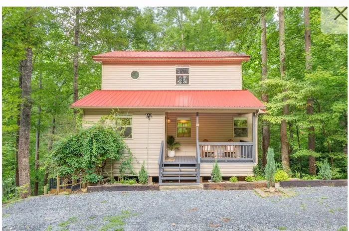 Cozy forest cabin with red roof, porch seating, and serene privacy.