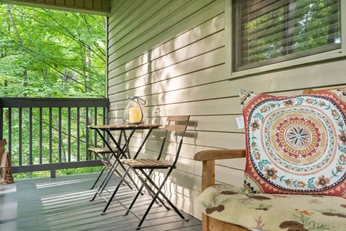 Peaceful covered porch with bistro seating and serene wooded views