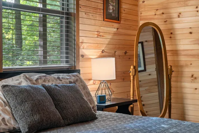 Cozy wood-paneled bedroom with forest views and warm cabin charm