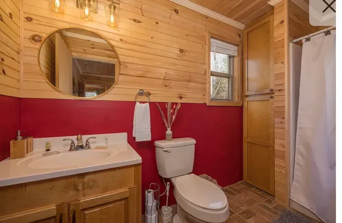 Rustic cabin bath with warm wood, window light, shower & storage