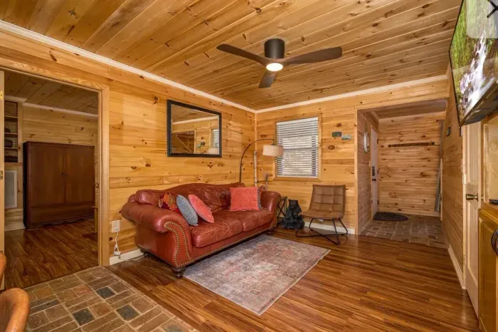 Cozy pine cabin lounge with leather sofa, smart TV & mudroom entry