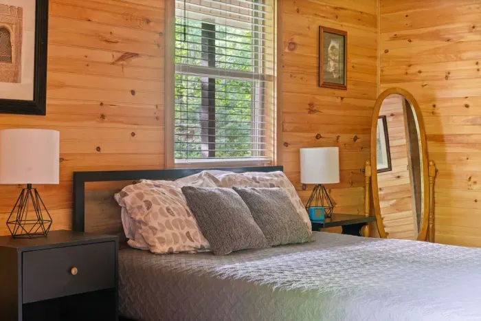 Cozy wood-paneled bedroom with forest views and inviting cabin charm
