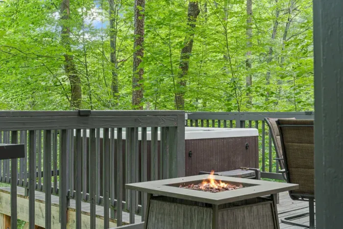 Private wooded deck with hot tub and fire table for cozy outdoor relaxation