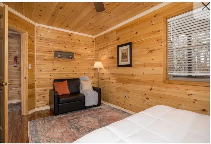 Cozy cabin bedroom with loveseat, rug, and bright natural light