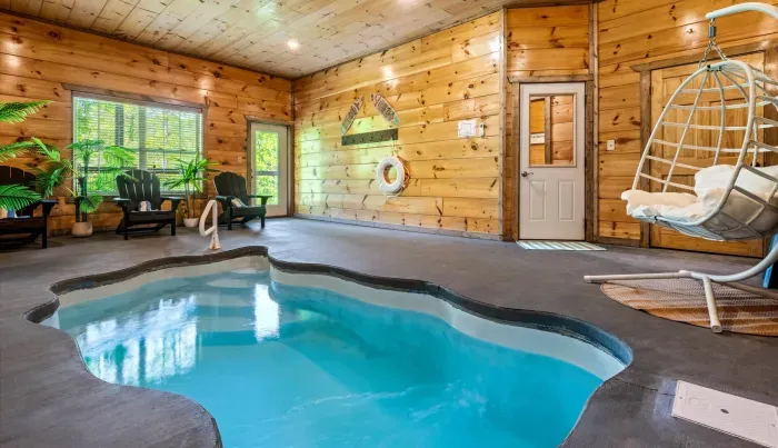 Private indoor pool in a rustic cabin with seating and swing chair