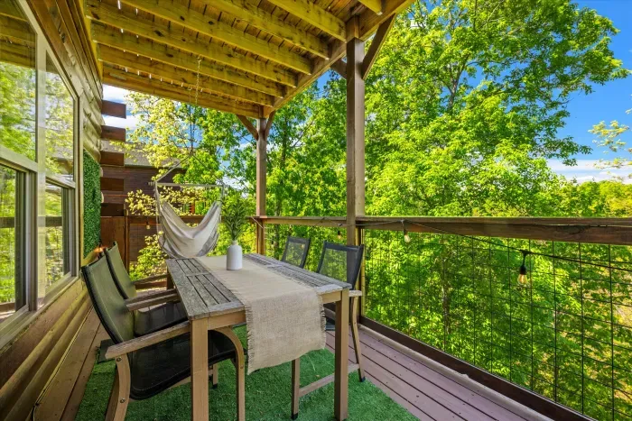 Covered treehouse deck with dining set, hammock chair & lights