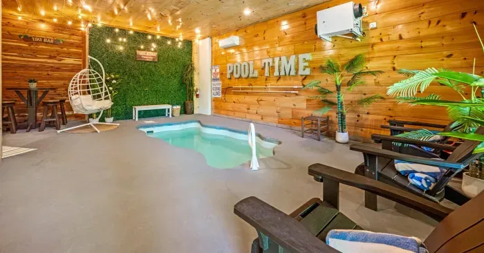 Indoor plunge pool oasis with tiki vibes, swing chair & string lights.