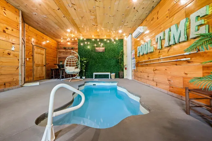 Cozy indoor pool oasis with string lights, greenery wall, and egg chair