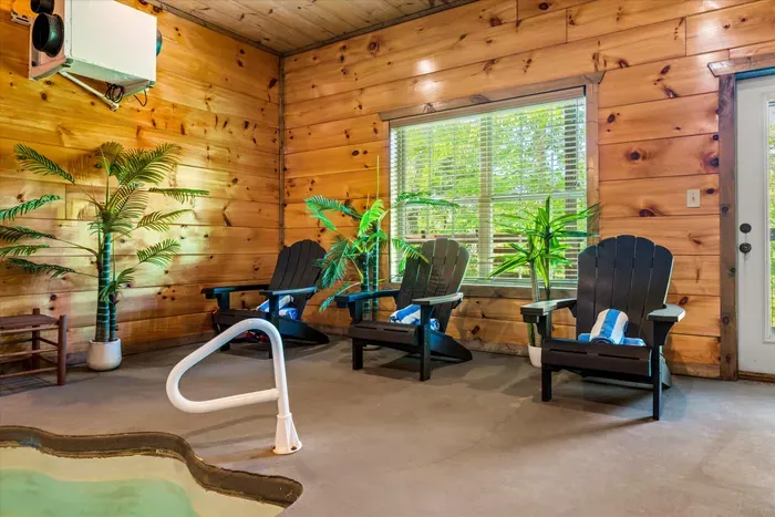 Cabin-style indoor pool lounge with Adirondacks and wooded views