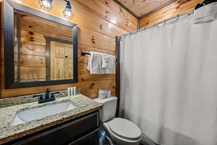 Cozy cabin bath with granite vanity, black fixtures, and tub/shower.