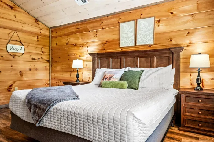 Cozy cabin king suite with warm wood walls and soft bedside lighting