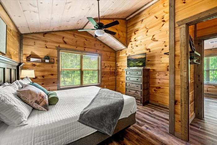 Cozy cabin bedroom with forest views, vaulted ceiling, and queen bed
