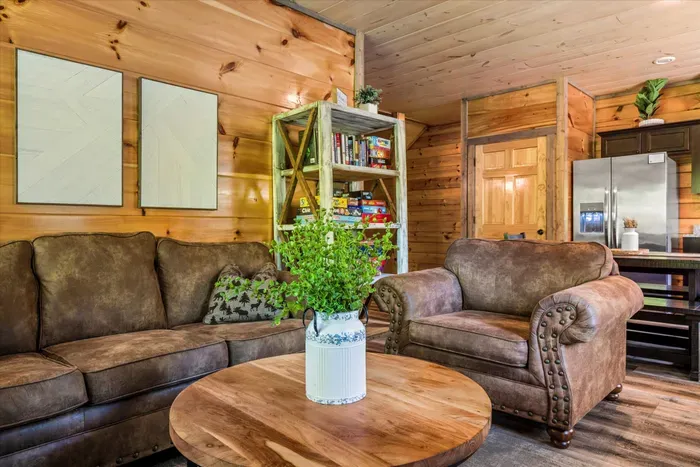 Cozy cabin lounge with leather sofas, games shelf, and open kitchen