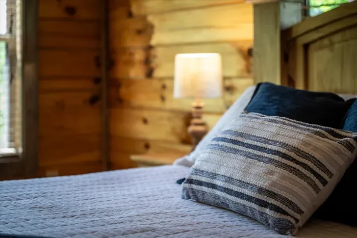 Rustic cabin bedroom with plush bedding and warm bedside glow