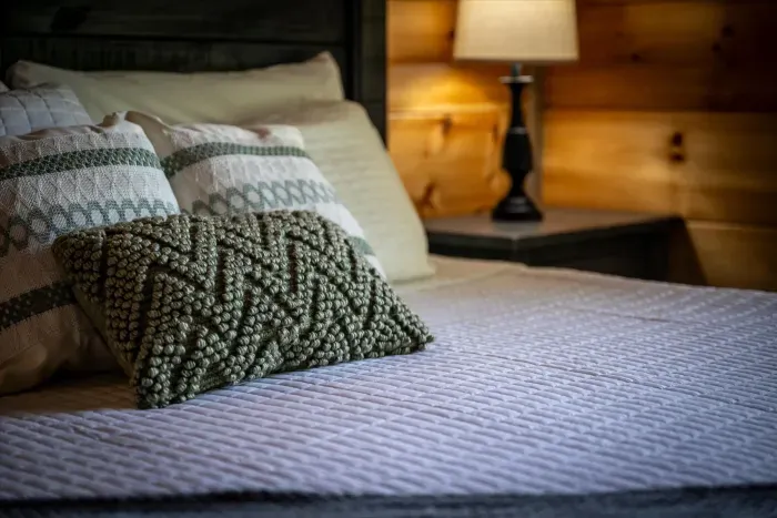 Cozy cabin bedroom with textured pillows and warm bedside lighting
