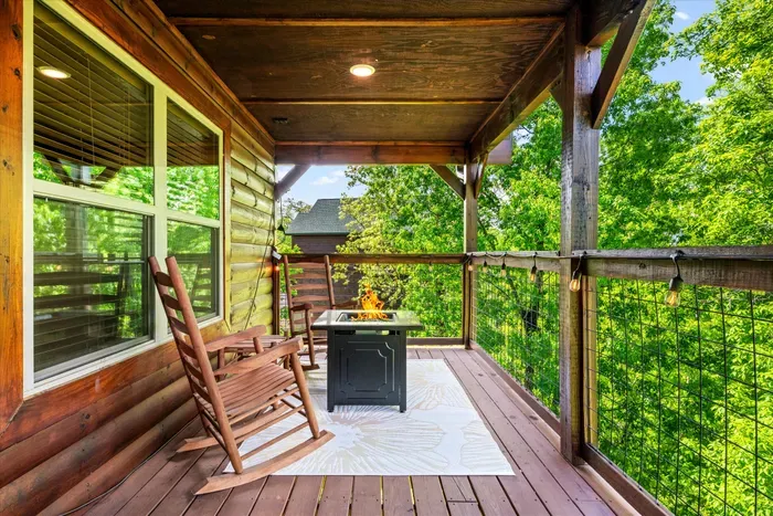 Cozy covered deck with propane fire pit, rocking chairs, cafe lights and lush forest views.