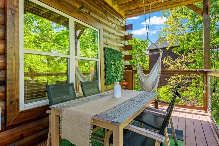 Cozy covered deck with dining set, swing chair, and treetop views
