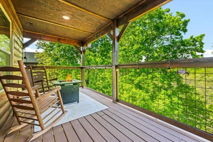 Covered deck with rocking chairs, fire table & treetop views