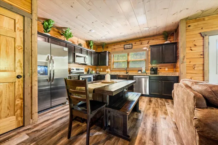 Sunlit rustic cabin kitchen, stainless appliances & farmhouse table