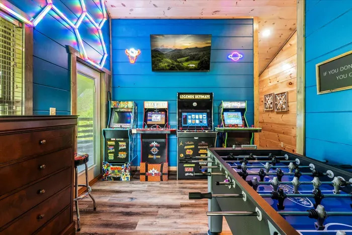 Colorful cabin game room with arcades, foosball, TV and neon glow