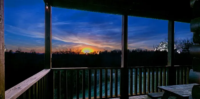 Covered cabin deck with sweeping sunset views over the treetops