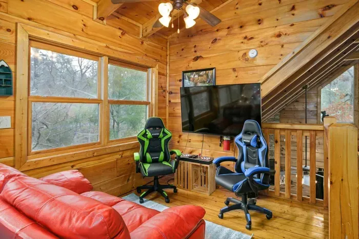 Loft movie area with smart TV, arcade, sofa, and gamer chairs 
