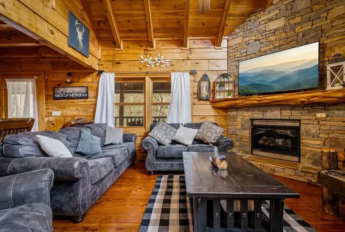 Cozy cabin lounge with stone fireplace, vaulted wood ceilings, and smart TV