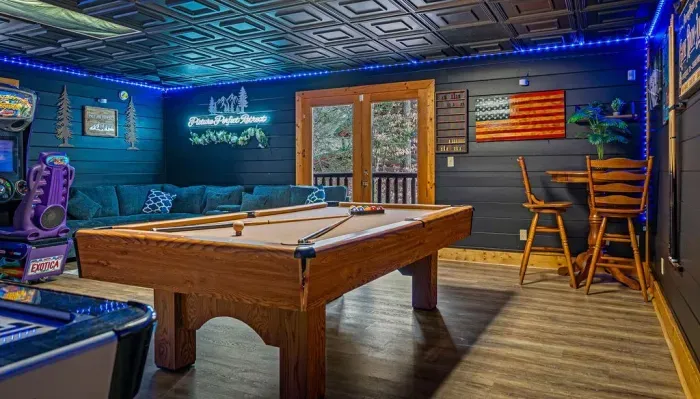 Rustic game room with pool, arcades & deck views—perfect hangout