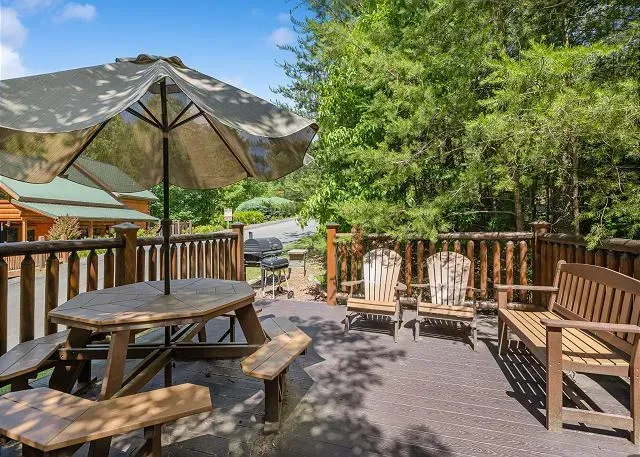 Sunny forest-view deck with umbrella dining, seating & grill