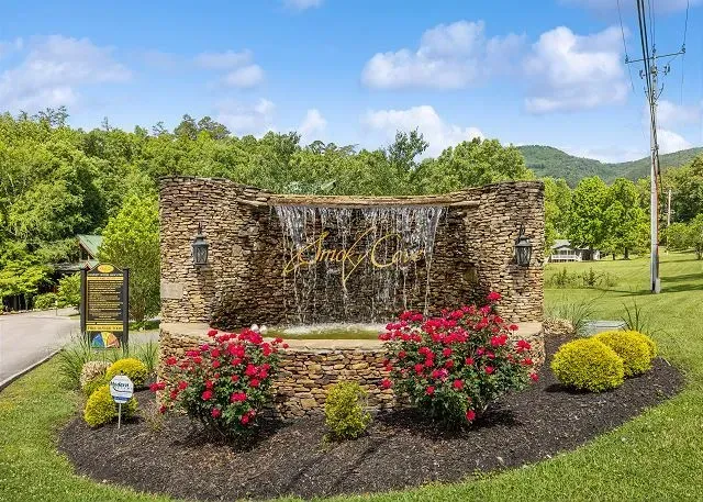 Resort-style stone waterfall entry amid lush gardens and mountain views