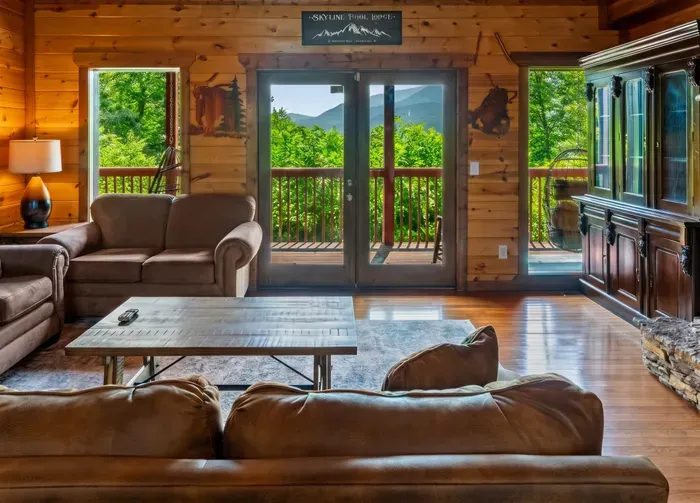 Cozy log cabin living room with deck access and mountain views