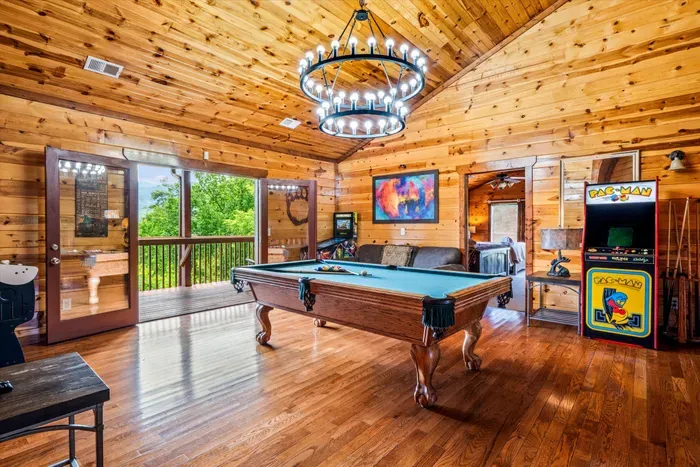 Rustic game room with pool table, arcade fun, and scenic deck access