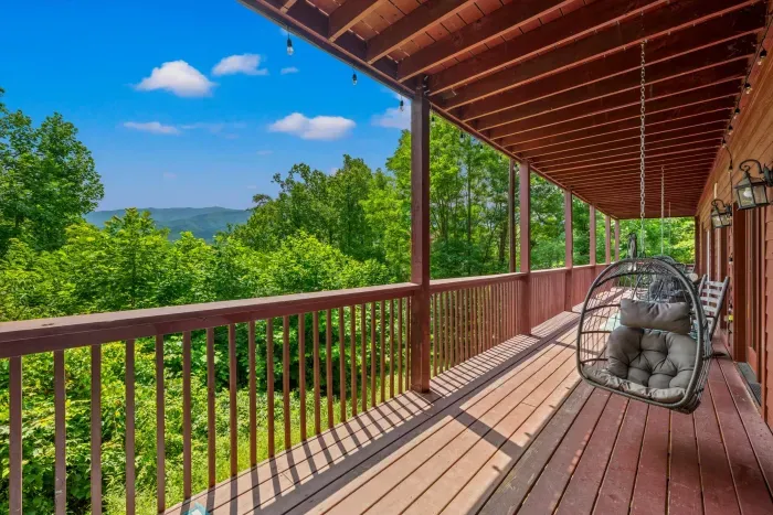 Covered mountain-view porch with cozy hanging chairs and forest scenery