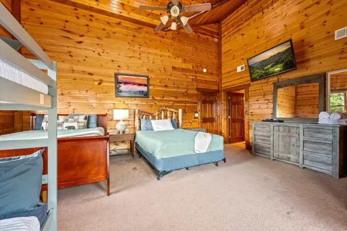 Spacious rustic bedroom with queen bed, bunks, and cozy cabin charm