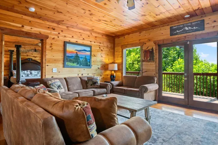 Cozy wood-lined living room with plush seating and scenic deck views