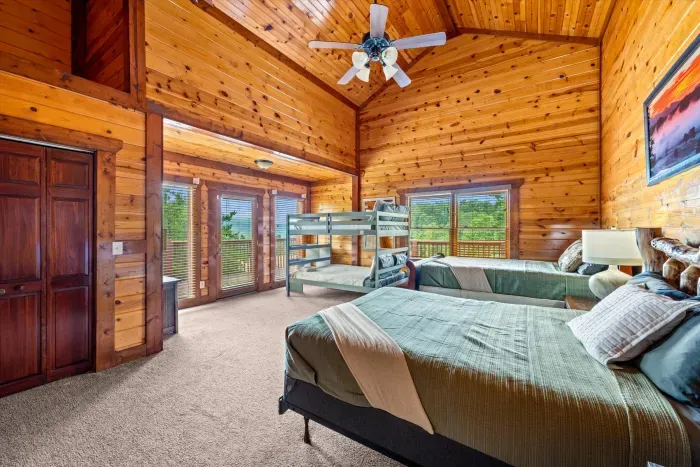 Spacious loft-style cabin bedroom with bunks, vaulted ceilings & deck access