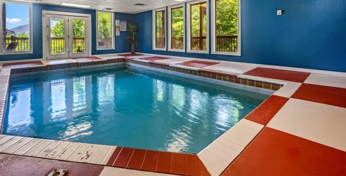 Bright indoor pool with large windows and peaceful wooded views