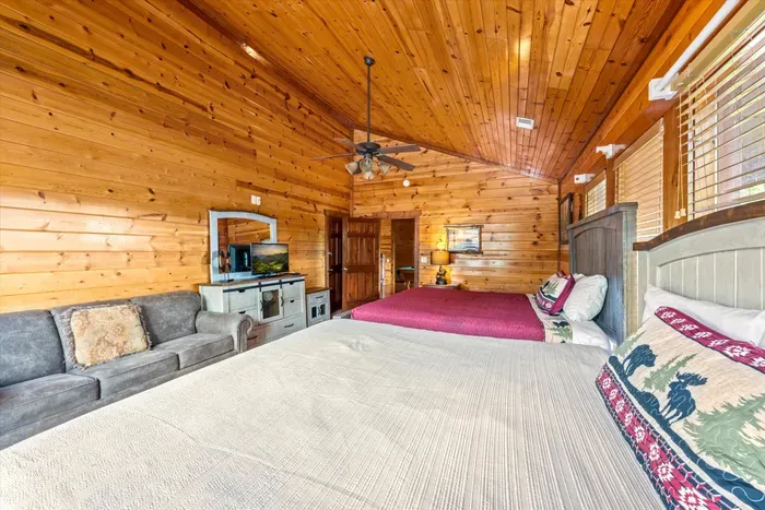 Spacious rustic bedroom with two beds, vaulted wood ceilings, and cozy cabin charm
