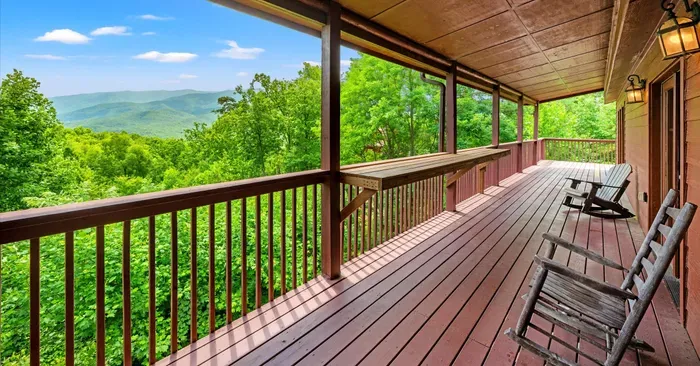 Covered mountain-view deck with rocking chairs and serene forest scenery