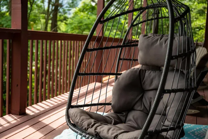 Cozy covered deck with a hanging chair and peaceful wooded views