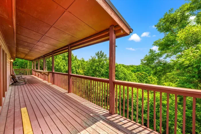 Expansive covered deck with rocking chairs and serene treetop views
