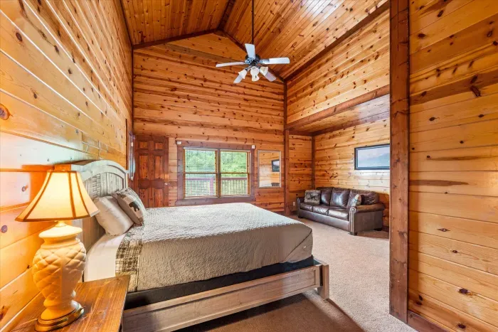 Spacious vaulted cabin bedroom with cozy seating and natural light